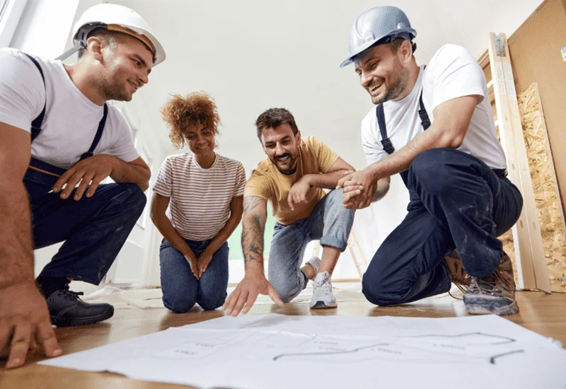 Artisans et clients discutent d'un plan d'aménagement intérieur